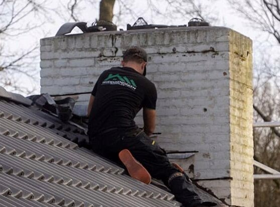 Dakdekker voert schoorsteenonderhoud uit op een dak