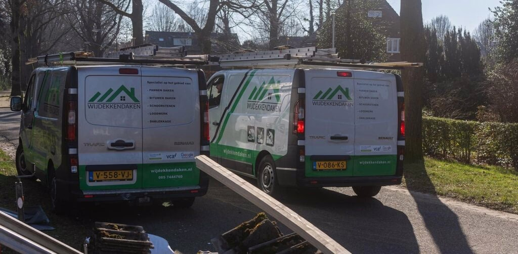 Bedrijfsbussen van WijDekkenDaken met dakmateriaal langs de weg