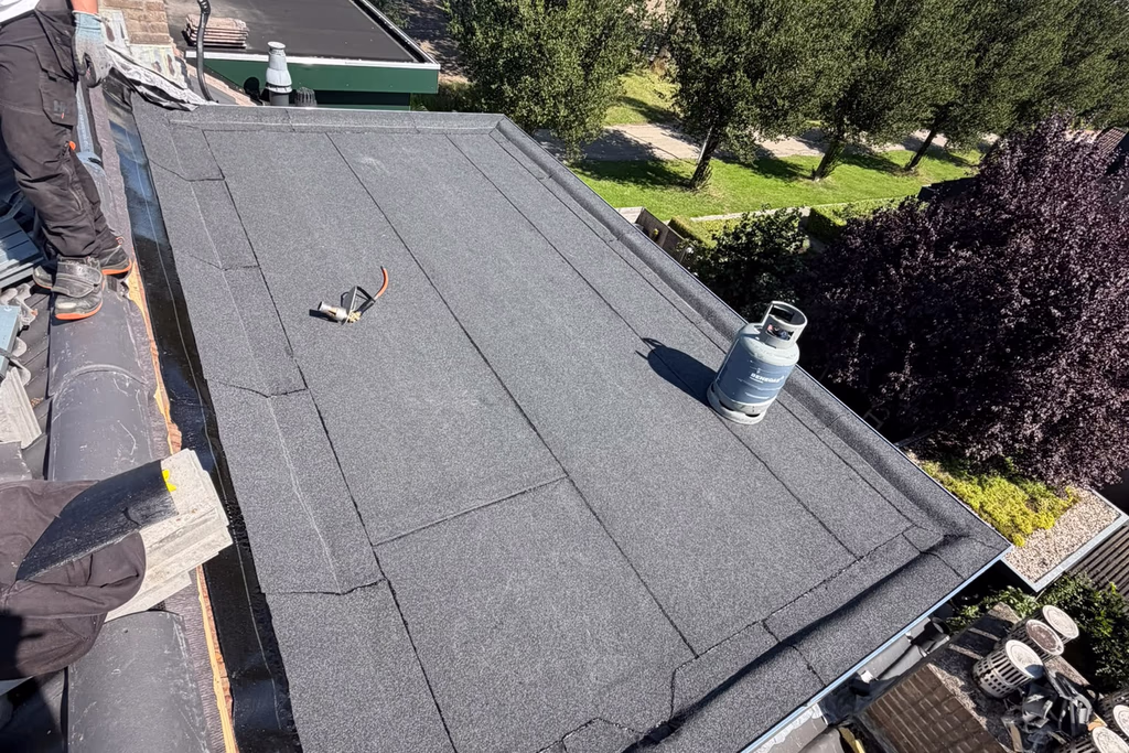 Nieuw bitumen plat dak naast een pannendak