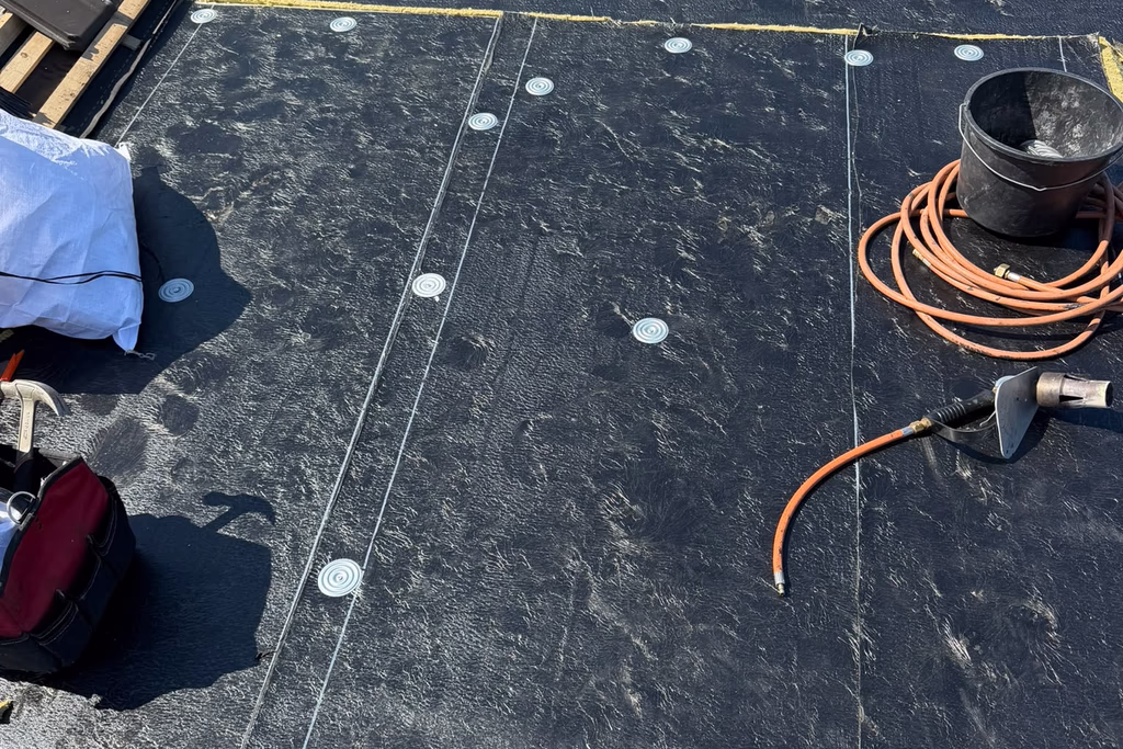 Bitumen onderlaag op een plat dak, tijdens het werk