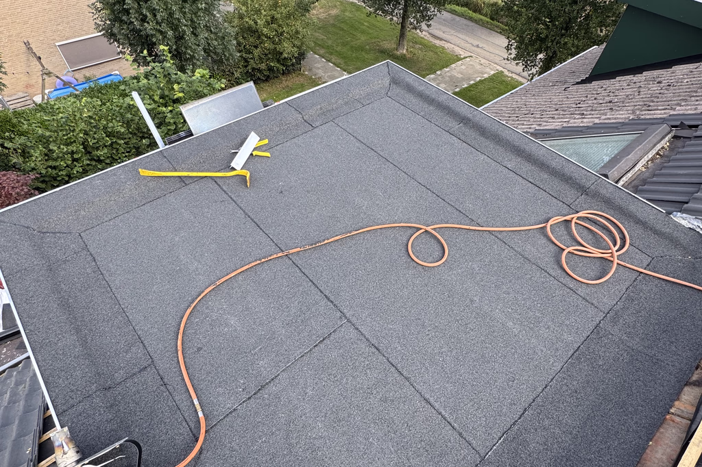 Nieuwe bitumen dakbedekking op een plat dak, tijdens het werk